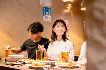 居酒屋でお酒を飲む若い男女