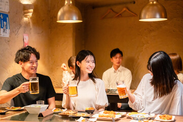 居酒屋でお酒を飲む若い男女
