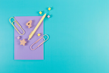 Top view of purple notebook on blue background. Paperclips, pen, number, shape and pins. School, office wallpaper. Flat lay, copy space.
