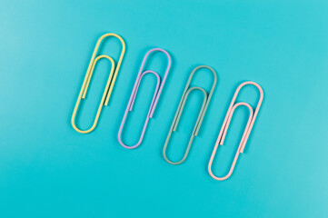Top view of colorful paperclips on blue background. School, office wallpaper. Flat lay, copy space.