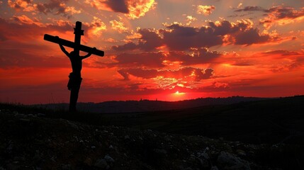 Silhouette of crucifix Jesus at sunset with dramatic red and orange sky