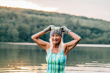 Cold water swimming for elderly women. Senior sporty women standing in lake during cold winter...