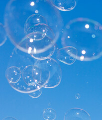 A bunch of bubbles floating in the air on a clear blue sky