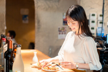 一人でカウンター席に座って焼き鳥を食べる女性