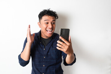Adult Asian man showing happy face expression while looking to the mobile phone screen