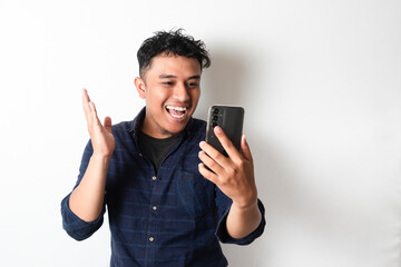 Fototapeta premium Adult Asian man showing happy face expression while looking to the mobile phone screen