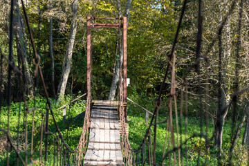 Obraz premium Rope bridge over Gauja, beautiful river bank, bridge connects both banks of Gauja, Vidagas village, Latvia