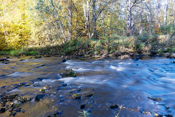 fast river between stones, stream of water passes the stone, ecology in the river, beautiful natural environment as background, blurred stream of water