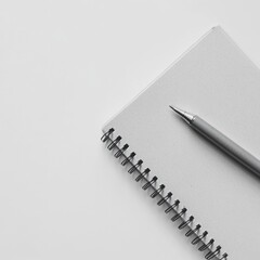 A minimalist notebook with a pen on a clean, white surface.