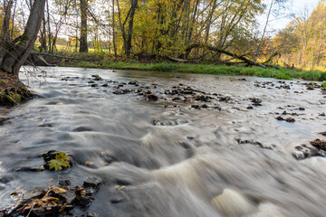 fast river between stones, stream of water passes the stone, ecology in the river, beautiful natural environment as background, blurred stream of water