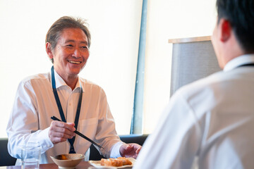 レストランでお昼ごはんを食べる二人のビジネスマン