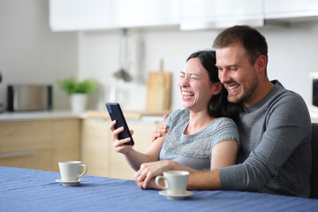Funny interracial couple laughing hilariously checking phone