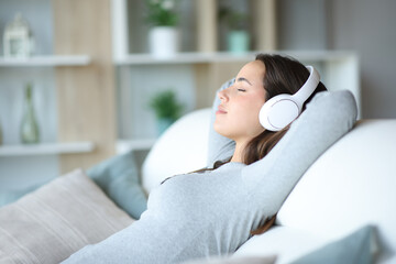 Woman relaxing listening audio with headphone sitting on a couch