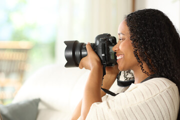 Black photographer taking photos with dslr camera at home