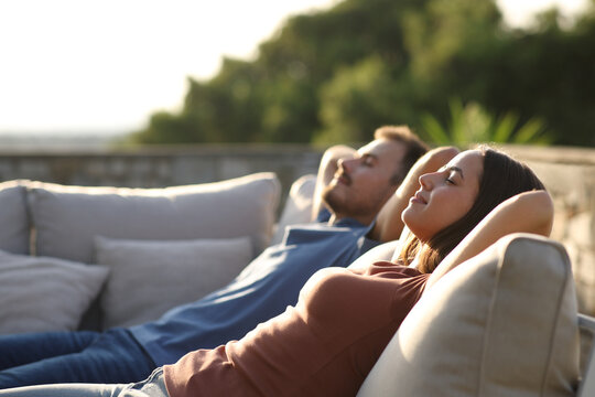 Relaxed couple sitting in an exterior sofa in a terrace