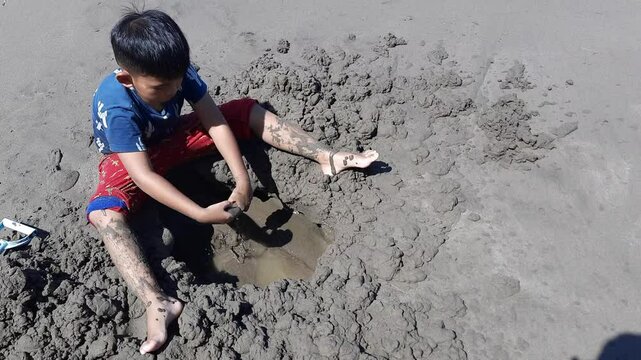 Indonesian Child Playing with Sand on Beach