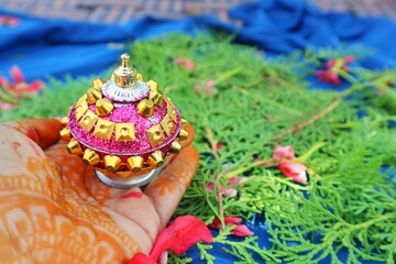 A decorative sindoor container filled with red sindoor powder, representing the concept of Karwa Chauth festival. Hold by mahendi hand , selective focus 