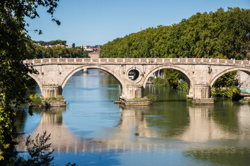 Fototapeta premium Old bridge over the Tiber River with water reflection in Rome, Italy 
