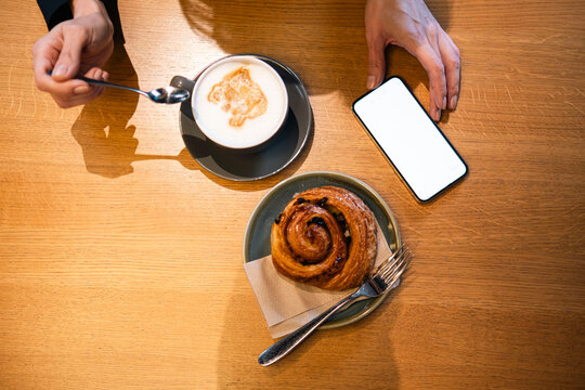 Mature woman using smart phone and having coffee at table
