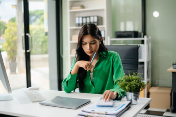 Frustrated young businesswoman working on a laptop computer sitting at his working place