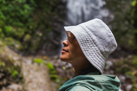 Woman wearing hat in front of waterfall