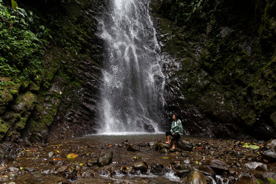 Woman sitting near waterfall in forest