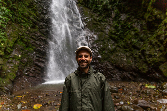Happy man standing in front of waterfall in forest