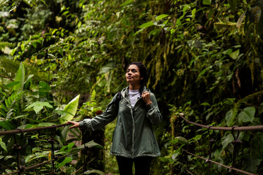 Smiling woman standing on bridge in forest