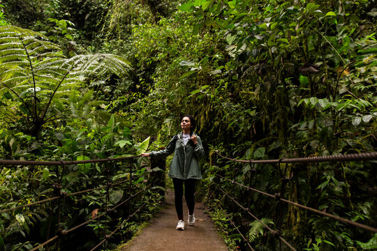 Woman walking on bridge near plants in rainforest