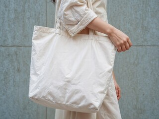 A minimalist woman hanging a white canvas tote bag , tote bag mockup