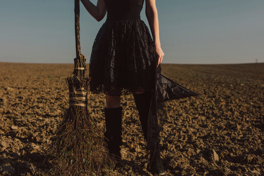 Woman standing with broom on field at Halloween