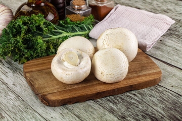 White champignon mushrooms heap over board
