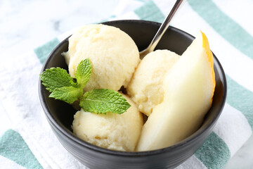 Scoops of tasty melon sorbet with mint and spoon in on white table, closeup