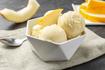 Scoops of tasty melon sorbet with fresh fruit in bowl on grey table, closeup