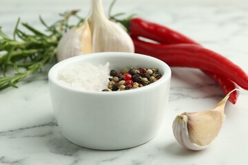 Sea salt, peppercorns, rosemary, chili peppers and garlic on white marble table, closeup