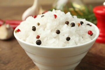Sea salt and spices in bowl on brown table, closeup