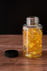 A bottle of yellow pills sits on a wooden table