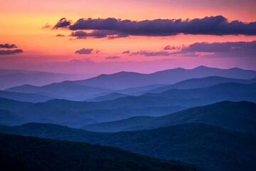 Obraz premium Layers upon layers of mountains fade into the horizon, under a soft, glowing sunset sky, radiating peacefulness and depth over the tranquil landscape.