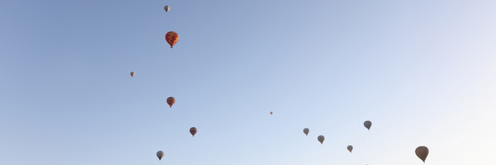 Multi-colored balloons floating up in air against blue sky