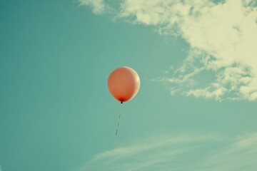 Obraz premium A single orange balloon floats peacefully in the sky, symbolizing freedom and joy. Wispy clouds create a serene backdrop, enhancing the uplifting mood.
