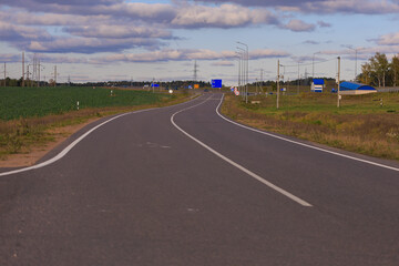 Wide road, highway, sun and blue sky on a summer day.
