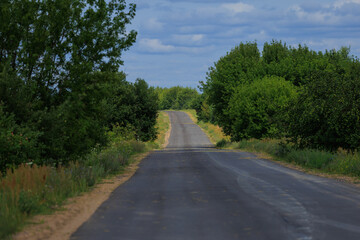 Wide road, highway, sun and blue sky on a summer day.