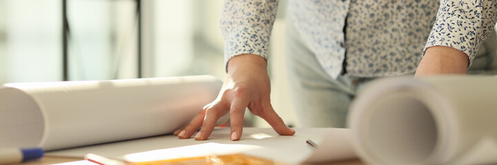 Female engineer unrolls large paper with building drawing