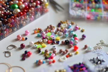 Colorful beads, letter beads, threads and other jewelry making supplies on white background. Making...