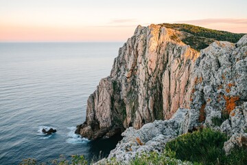Golden hour light bathes the rugged cliffs facing the ocean with a warm glow, enhancing their textures and revealing hidden details in the breathtaking landscape.