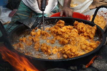 Mix vegetable pakora making and being displayed by a street food vendor, Crispy onion and potato pakoda selling on a market, Spicy veg pakora or pakoda displayed on a rural fair for sale
