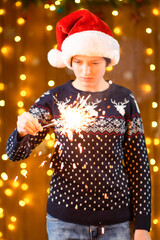 A teenage girl poses with sparklers, decorations for the New Year holiday, festive illumination and garlands