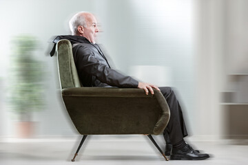 Shocked senior businessman sitting in chair with blurred backgro