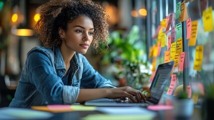 Obraz premium Woman working on a laptop surrounded by colorful sticky notes.