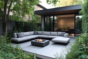 Fototapeta premium A contemporary outdoor area features a cozy sectional sofa set around a sleek firepit, all surrounded by lush vegetation for an intimate and warm ambiance.